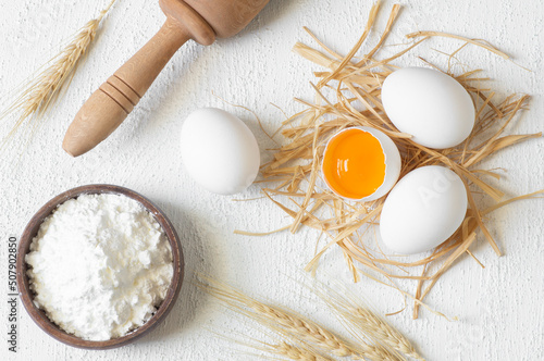 Preparing dough, baking ingredients flour eggs on white table