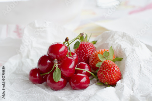 Fresh cherries and strawberries placed on a paper towel close-up