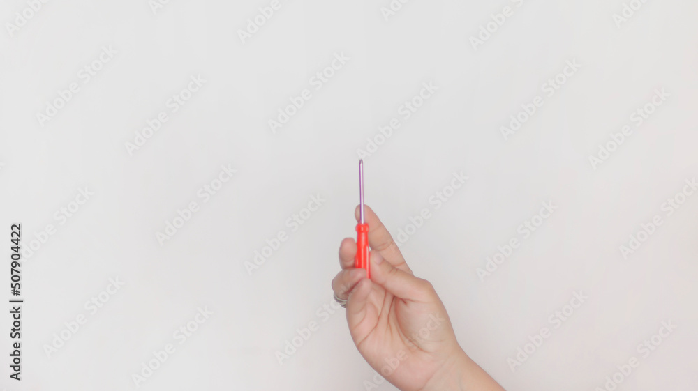 Hand holding a small red cross-tipped screwdriver on white background. Hand holding a small red cross-tipped screwdriver on white background.