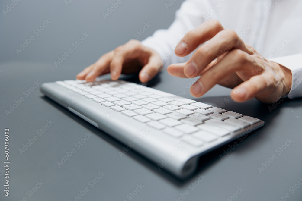 worker sitting at a table with a keyboard in the office Gray background worker sitting at a table with a keyboard in the office Gray background