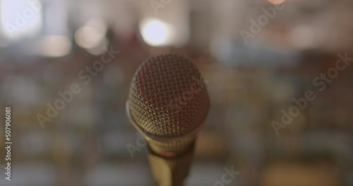 Close-up of a microphone grid. Protection of the broadcasting device in the reproduction of the voice of the host of the event. Background in bokeh. Handheld shooting.