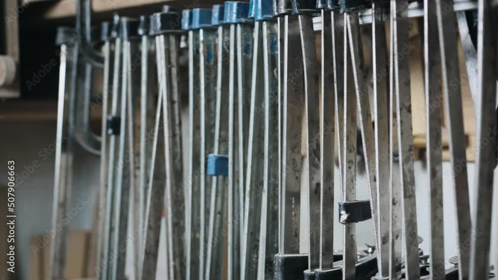 Many different clamps in the carpentry workshop. The tool hangs near the wall. Many different clamps in the carpentry workshop. The tool hangs near the wall.