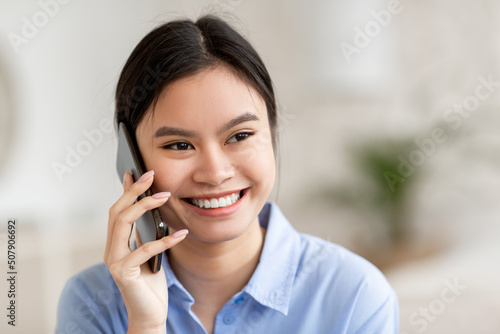 Closeup of smiling asian woman talking on cell phone