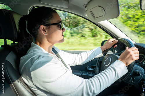 Condutora concentrada com as mão no volante a conduzir o carro enquanto viaja photo
