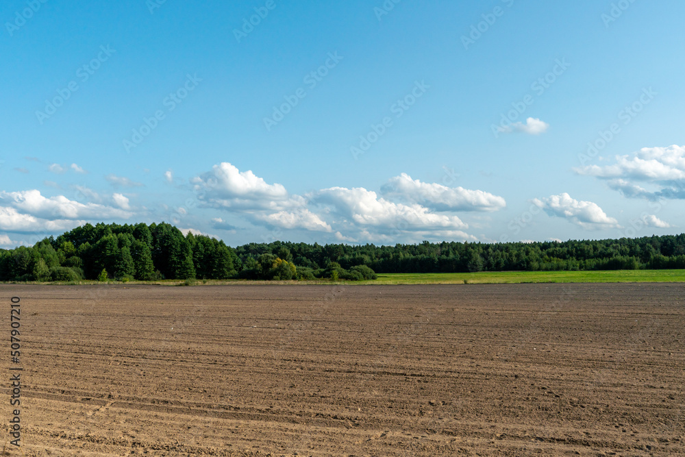 beautiful rural landscape. Hilly plowed agricultural fields against the background of clouds. The play of light and shadow on a hilly landscape.