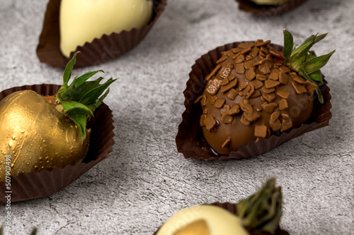 Closeup of strawberries covered inwhite and milk chocolate.Side view photo