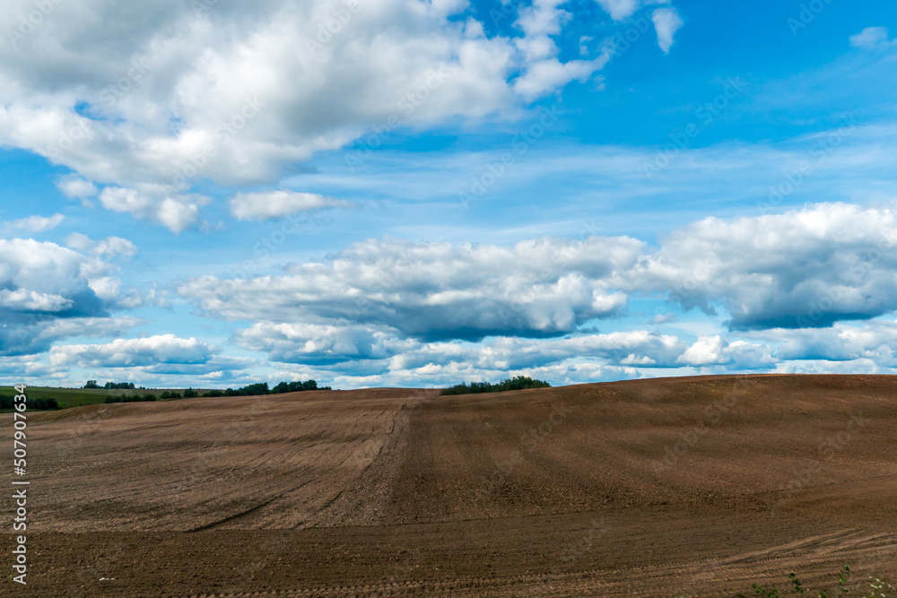 A plowed field against the sky. The season of planting crops in a wheat field. Preparing the field for planting rapeseed, wheat, rye and barley in rural areas.