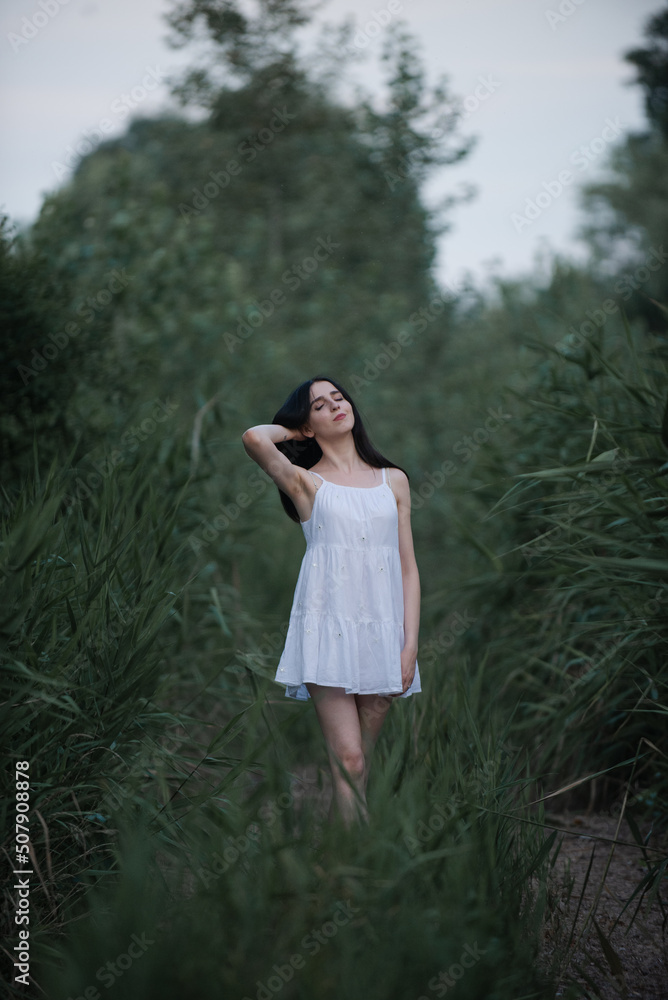Beautiful sexy girl in a short white dress in nature near the river