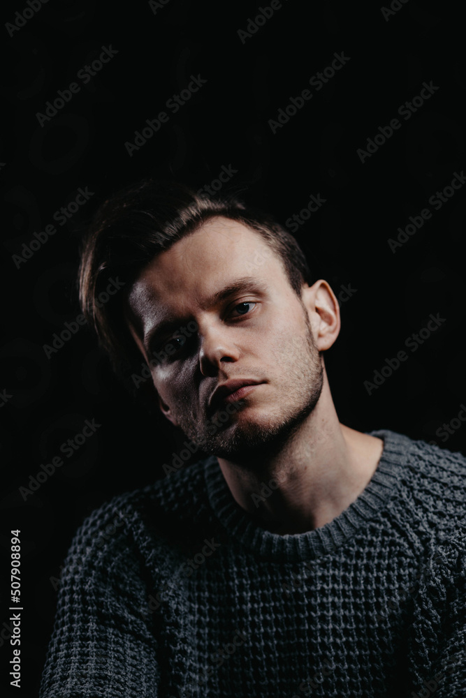 handsome young man in a knitted black sweater in the studio on a dark background. Sensual man portrait. handsome young man in a knitted black sweater in the studio on a dark background. Sensual man portrait.