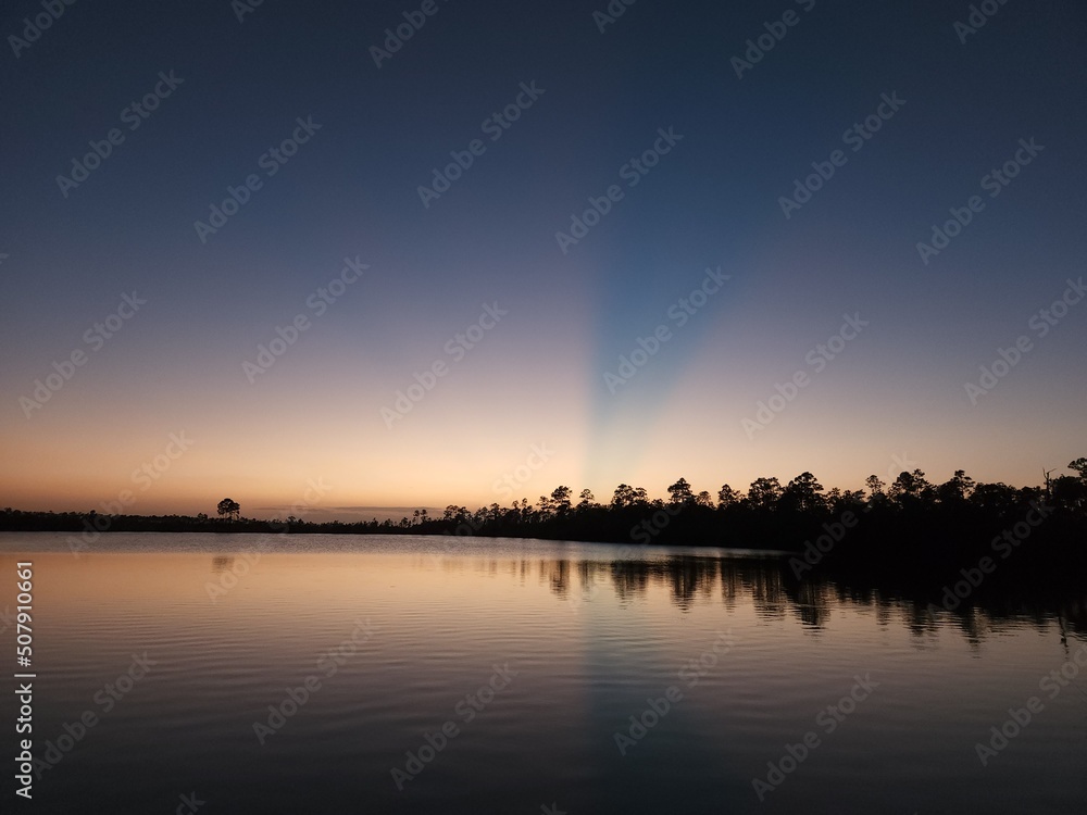 Sun rays in twilight over Pine Glades Lake in Everglades National Park, Florida on calm clear April evening. Sun rays in twilight over Pine Glades Lake in Everglades National Park, Florida on calm clear April evening.