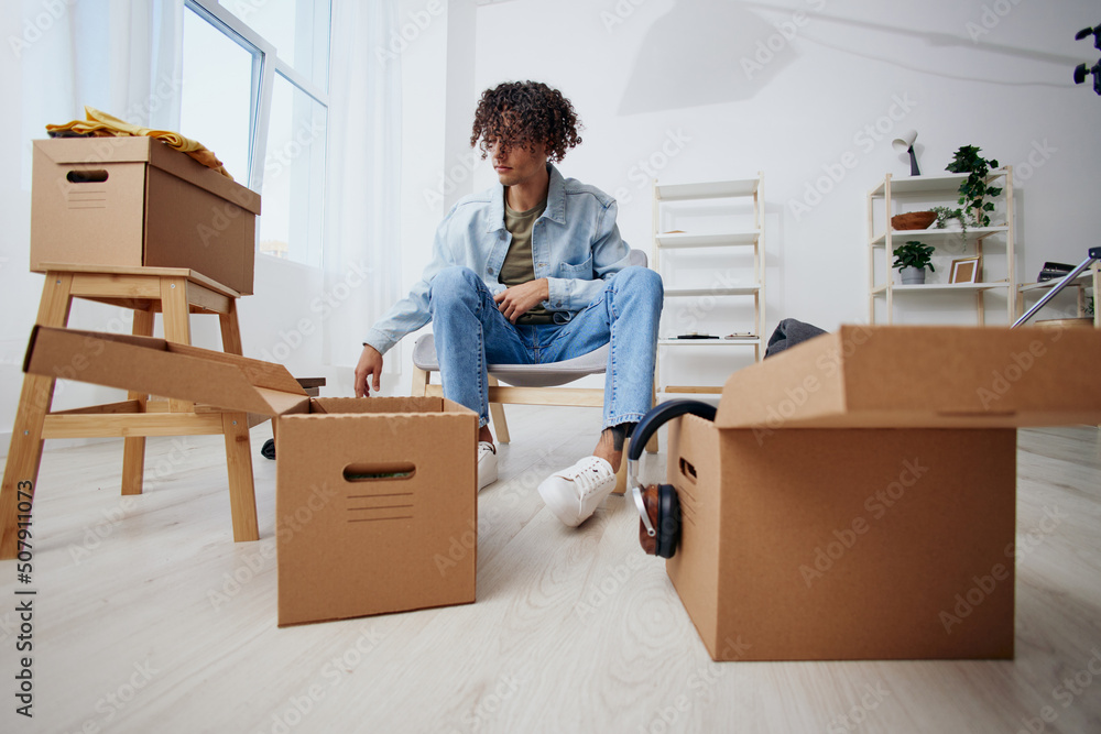 handsome guy sitting on a chair with boxes moving interior handsome guy sitting on a chair with boxes moving interior