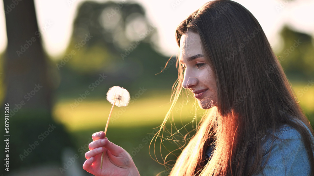 A young girl gently looks at the dandelion flower. A young girl gently looks at the dandelion flower.