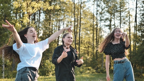 Joyful girls are dancing on a picnic near the forest.