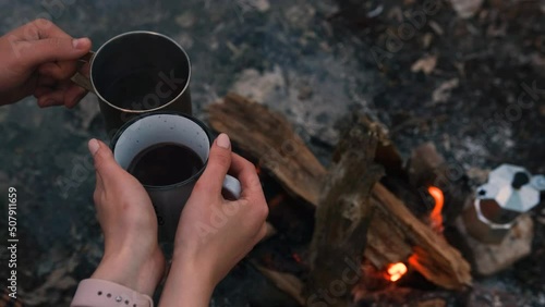 Couple in love Campsite With Fire Pit and Two Tin Cups with hot tea, coffee. Burning Campfire.
