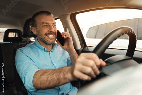 Happy man talking on smartphone while driving car © Prostock-studio