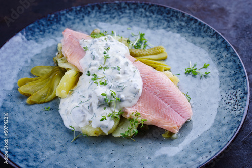 Modern style traditional smoked rainbow trout with boiled potato salad and mayonnaise served as close-up on a design plate
