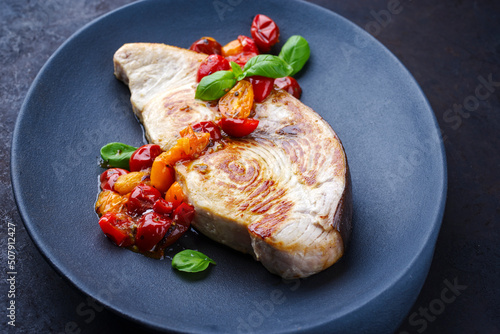 Bilde på lerret Fried swordfish steak with tomatoes and paprika served as close-up on a design p