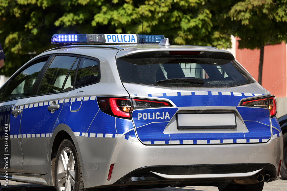 Radiowóz polskiej policji w mieście podczas patrolu.  - obrazy, fototapety, plakaty 