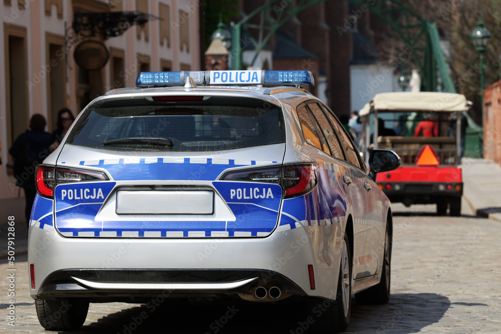 Radiowóz polskiej policji w mieście podczas patrolu.  - obrazy, fototapety, plakaty 