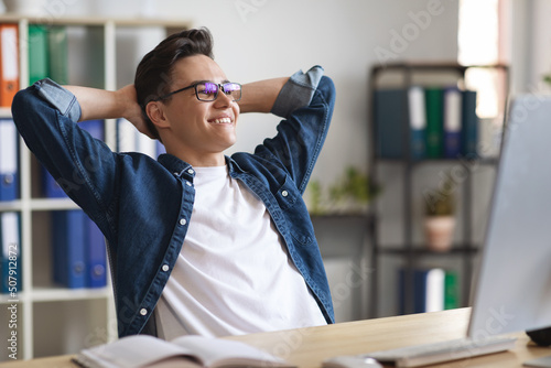Portrait Of Smiling Young Male Entrepreneur Relaxing At Workplace In Office