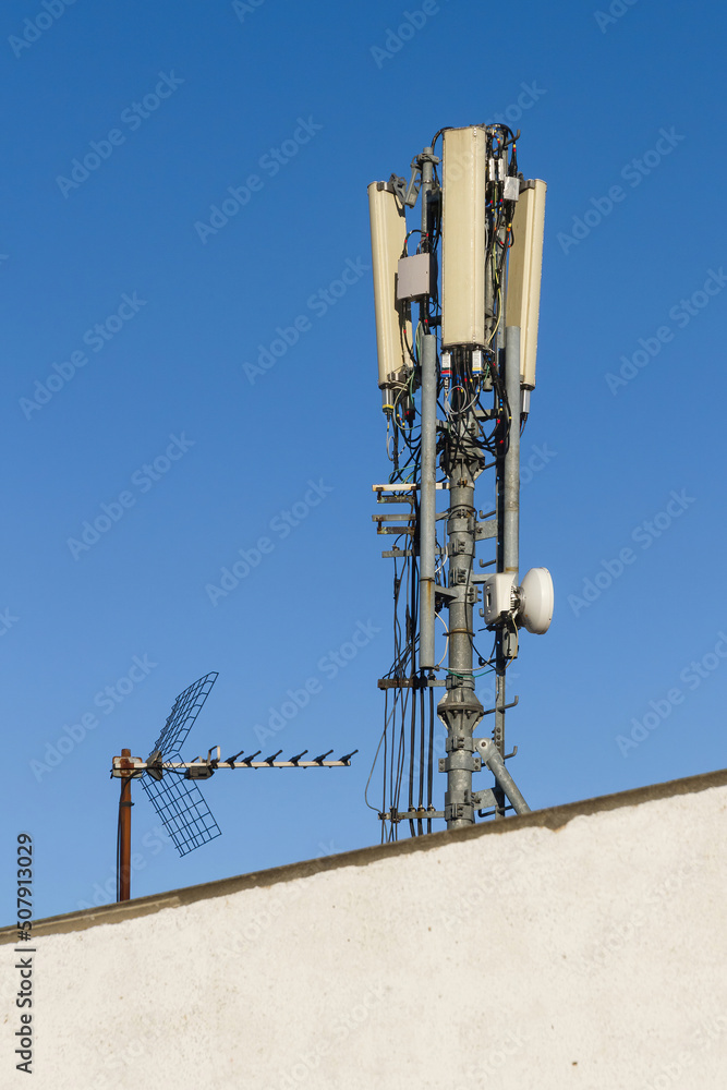 Mobile phone antennas with their connections and wiring on roof of building next to with television antenna Mobile phone antennas with their connections and wiring on roof of building next to with television antenna