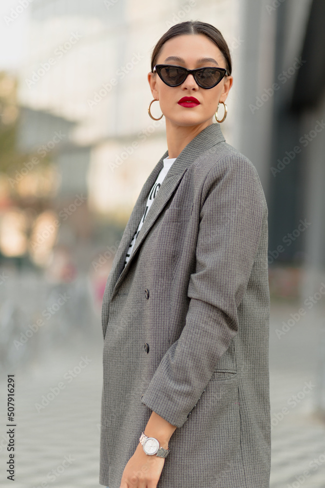 Spectacular charming lady in sunglasses and jacket with red lips posing outside. Caucasian woman posing outside.