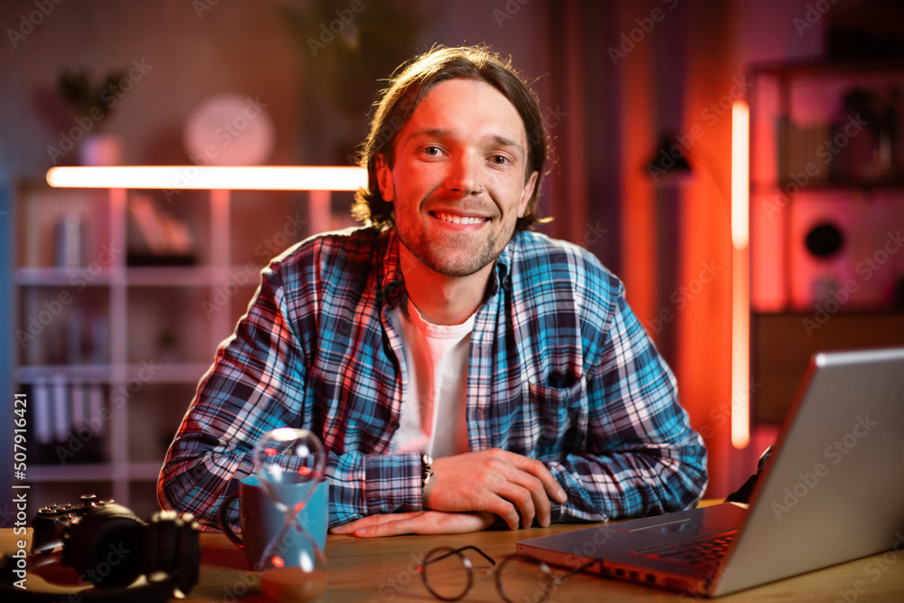 Attractive man sitting at desk with hands crossed on the chest and looking at camera. Caucasian male in casual wear taking break during process hours at home. Attractive man sitting at desk with hands crossed on the chest and looking at camera. Caucasian male in casual wear taking break during process hours at home.