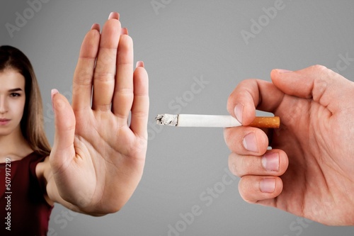 Woman showing stop sign with hand and refusing to take cigarette. No smoking concept