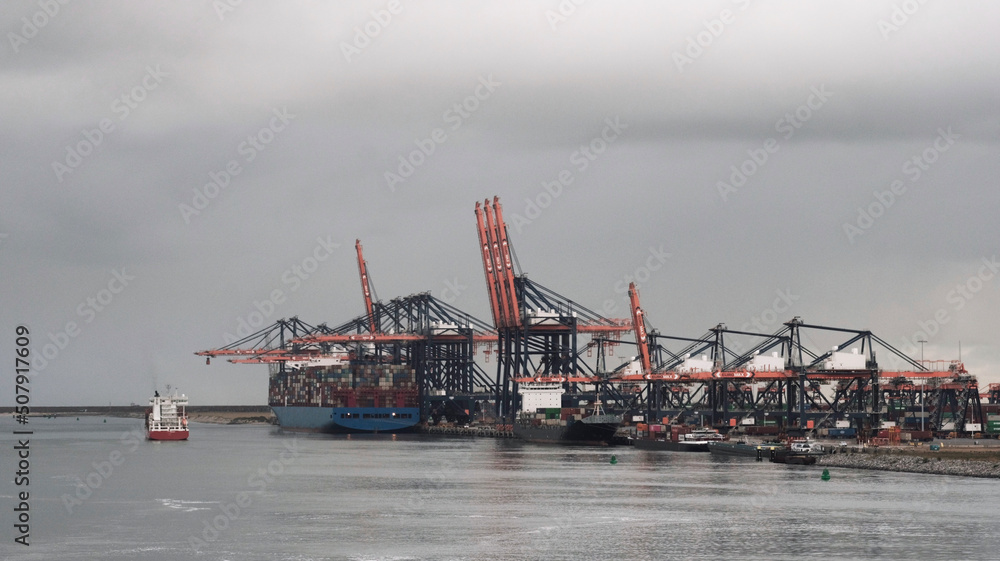 Port of Rotterdam, the Netherlands - 09 20 2021: Large and small container vessels moored alongside the container terminal for loading and discharging of cargo Port of Rotterdam, the Netherlands - 09 20 2021: Large and small container vessels moored alongside the container terminal for loading and discharging of cargo
