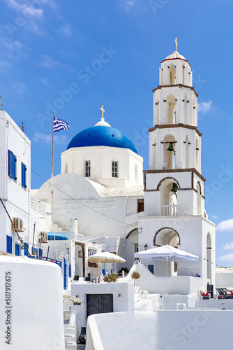 White church with a blue dome on Santorini island in Greece. Hot summer sun day.