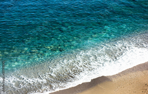 Top view of the turquoise sea surrounded by a deserted beach