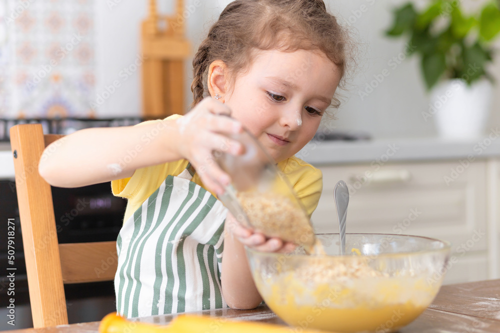Happy child playing with flour in kitchen. kid cooking food. little cute girl in apron in preparing dough, baking pie, oatmeal cookies, making biscuit Happy child playing with flour in kitchen. kid cooking food. little cute girl in apron in preparing dough, baking pie, oatmeal cookies, making biscuit