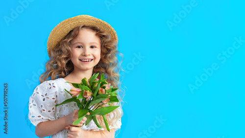 Happy little beautiful cute smiling girl with teeth, bouquet on blue background. Child with astromeria flowers. spring holiday kid, peace concept, international womens, March 8, mothers day. banner photo