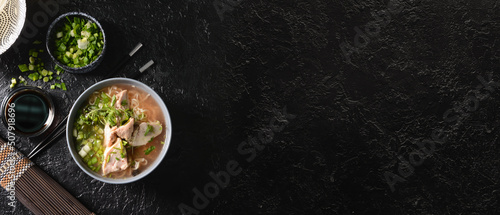 Bowl of tasty Chinese soup on dark background with space for text