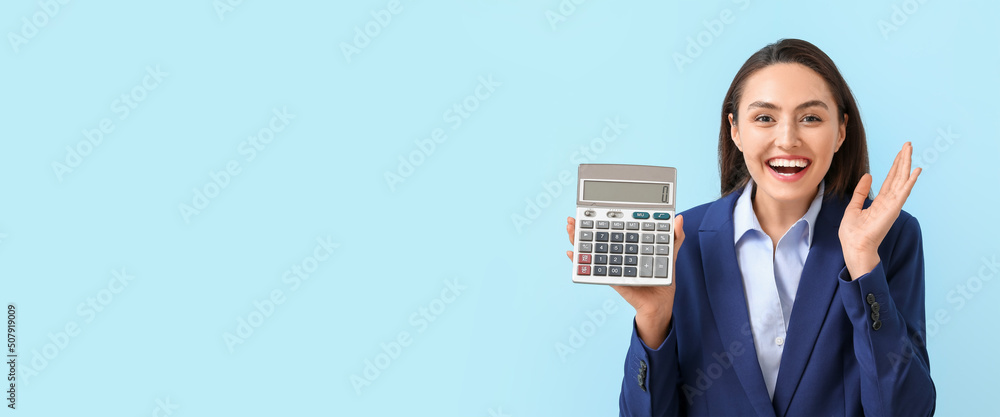 Happy young businesswoman holding calculator on light blue background with space for text Happy young businesswoman holding calculator on light blue background with space for text