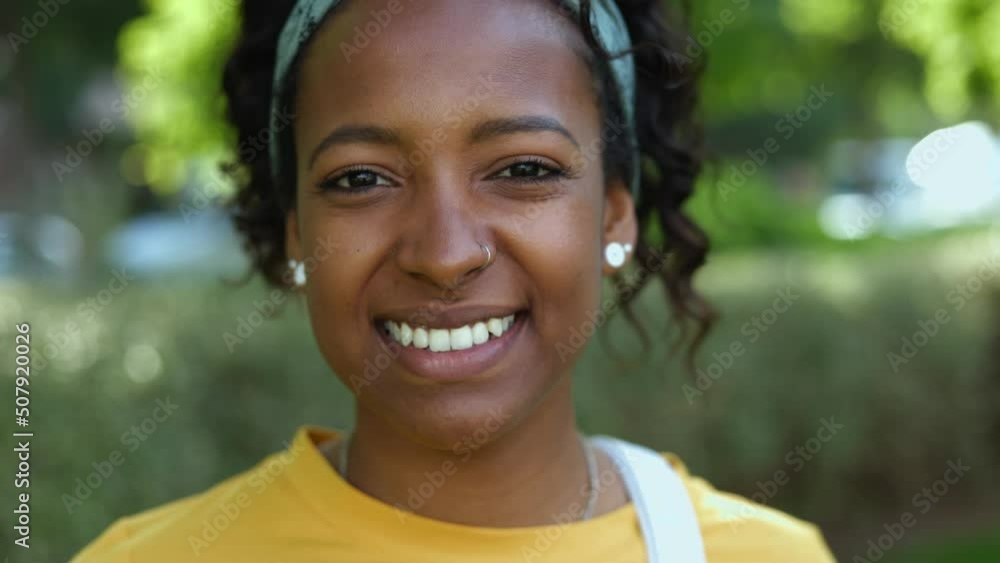 Close up portrait of pretty young african american woman smiling at camera. Happy lifestyle people concept with millennial teenager female student laughing outdoors Close up portrait of pretty young african american woman smiling at camera. Happy lifestyle people concept with millennial teenager female student laughing outdoors