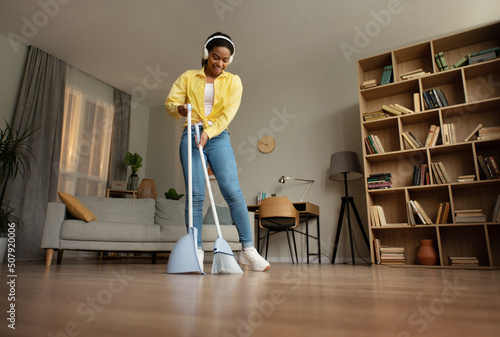 Happy Black Woman Sweeping Floor With Broom Cleaning Home