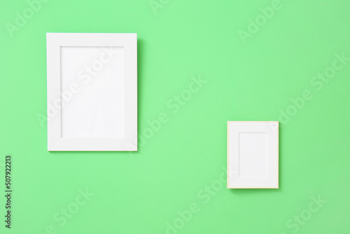 Blank photo frames hanging on green wall © Pixel-Shot