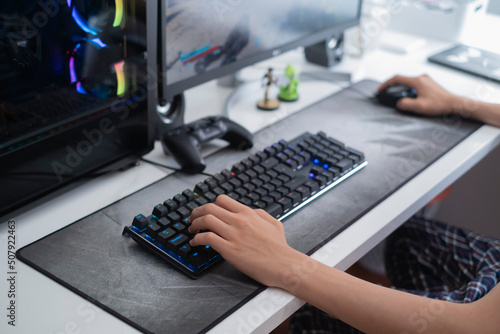 selective focus of a teenager's hands playing on a gaming computer, with a black keyboard on a large gray mouse pad, video game addiction problem photo