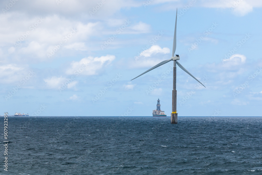 Isolated wind turbine in the Telde sea, town of Gran Canaria island with boats in the background. Offshore wind power