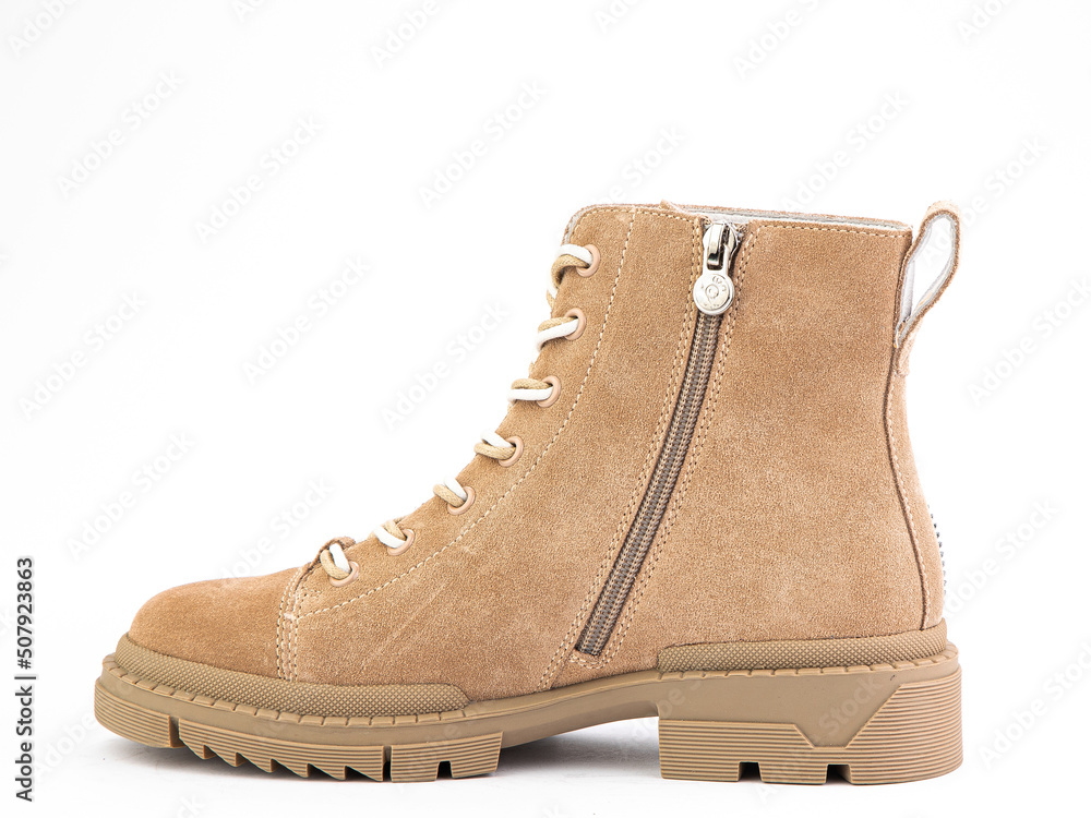 Beige suede boots with beige laces and zipper on the side. Elasticated side details and rubber sole. Isolated close-up on white background.