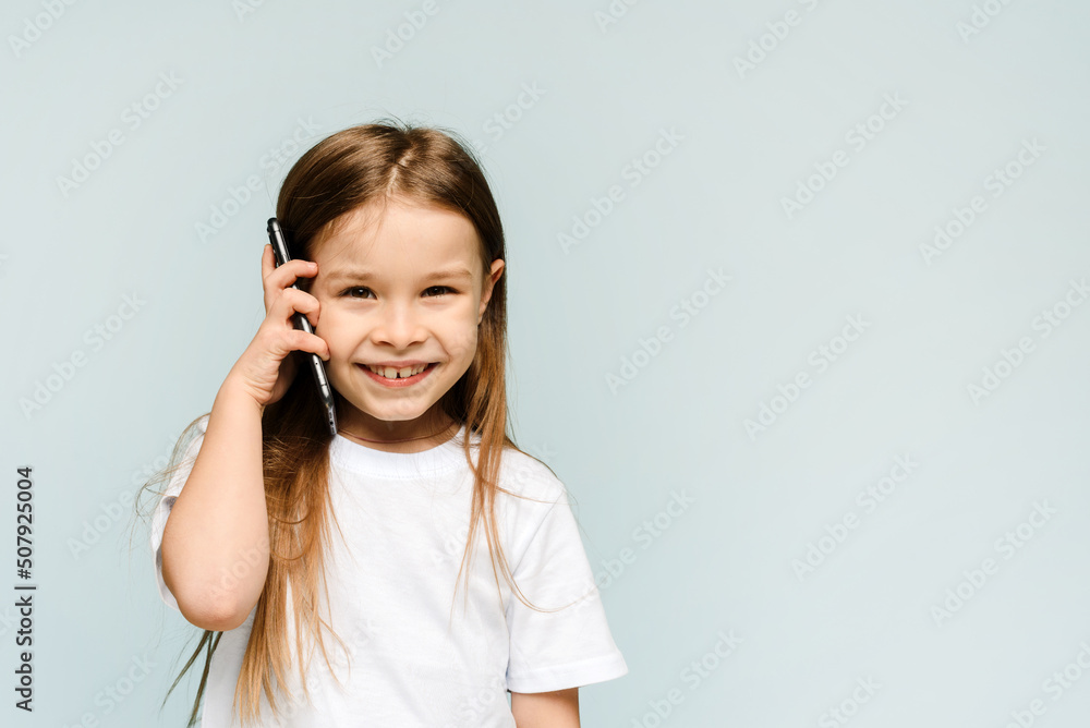 Cute caucasian baby girl talking on the phone, isolated in studio with blue background, little girl listening to news from mom Cute caucasian baby girl talking on the phone, isolated in studio with blue background, little girl listening to news from mom