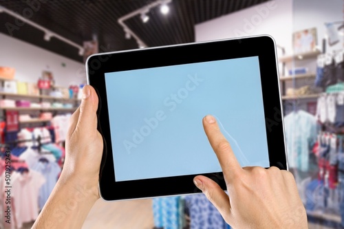 Smart store management systems concept. Manager using digital tablet on blurred store as background