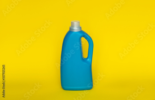 Softener in blue plastic bottle isolated on yellow background. Bottle with liquid laundry detergent, cleaning agent, bleach or fabric softener. Product design. Mock up.