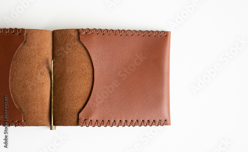 Open orange men's money clip handmade leather wallet. Empty money clip wallet with a two pockets for cards lies on a white table. Selective focus, copy space.