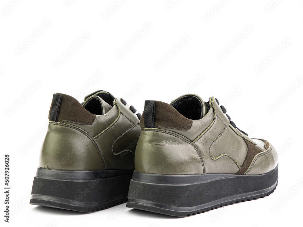 Green leather classic sneakers with laces. Casual men's style. Black rubber soles. Isolated close-up on white background. Back side view.