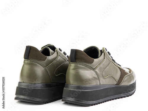 Obraz na płótnie Green leather classic sneakers with laces. Casual men's style. Black rubber soles. Isolated close-up on white background. Back side view. w salonie
