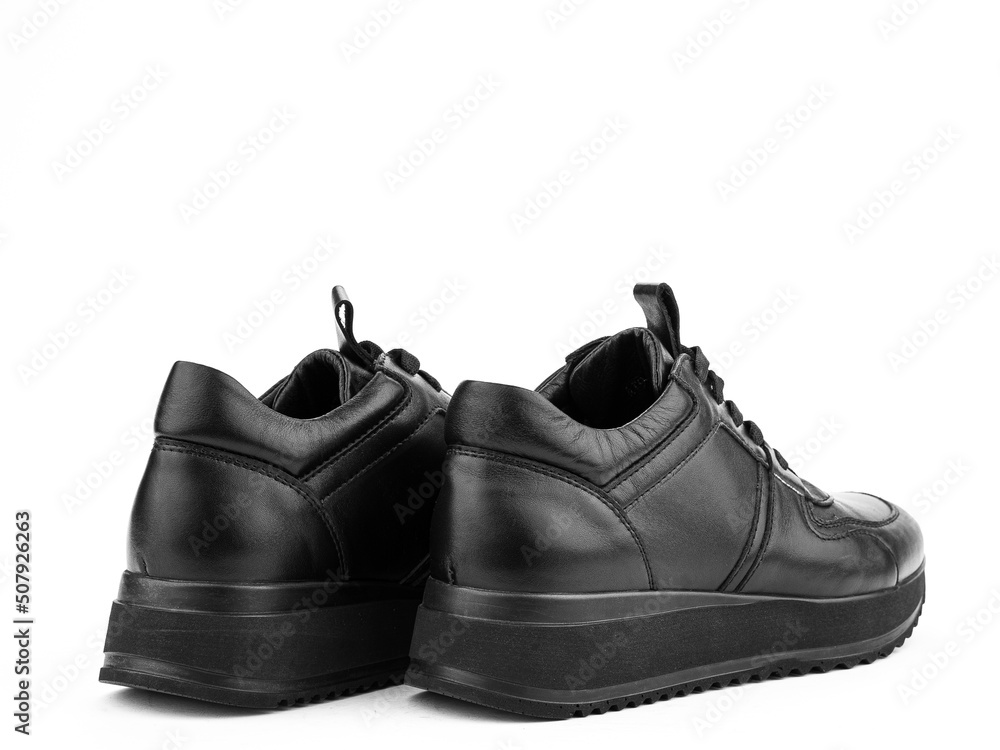 Black leather classic sneakers with laces. Casual men's style. Black rubber soles. Isolated close-up on white background. Back side view.