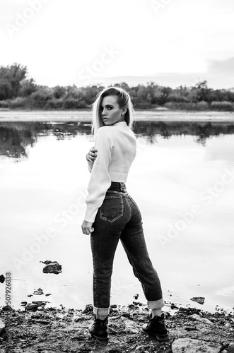 Fashionable portrait of a beautiful young woman outdoors. Black and white vertical photo. Casual style
