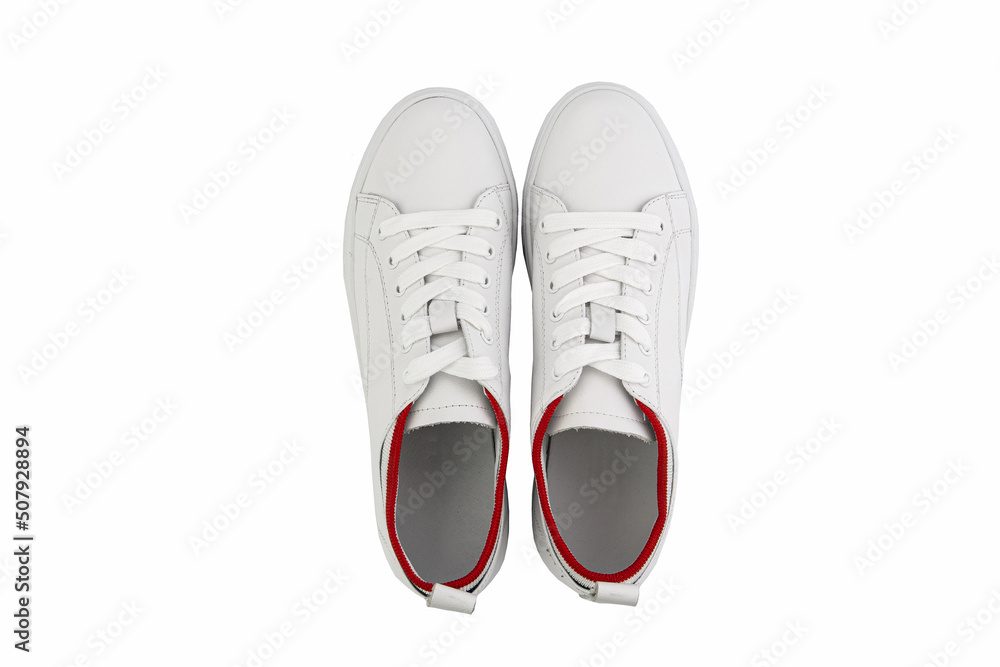 White leather sneakers. Casual women's style. White lacing and white rubber soles. Isolated close-up on white background. Top view. Fashion shoes